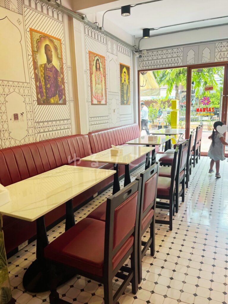 ボルドーのソファ席と白いテーブルが並ぶZafran Eateryの店内